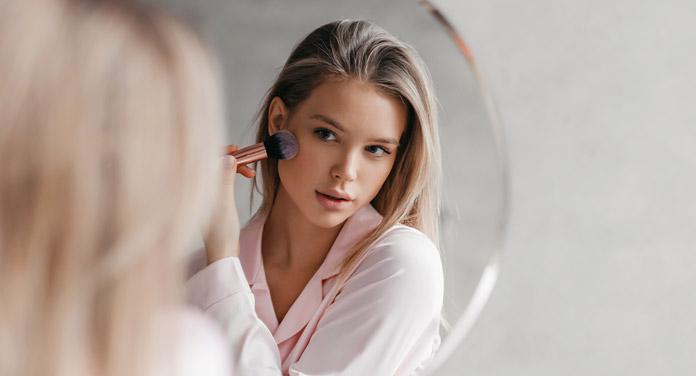 junge Frau vor dem Spiegel schminkt sich mit dem L-Shape-Blush-Hack